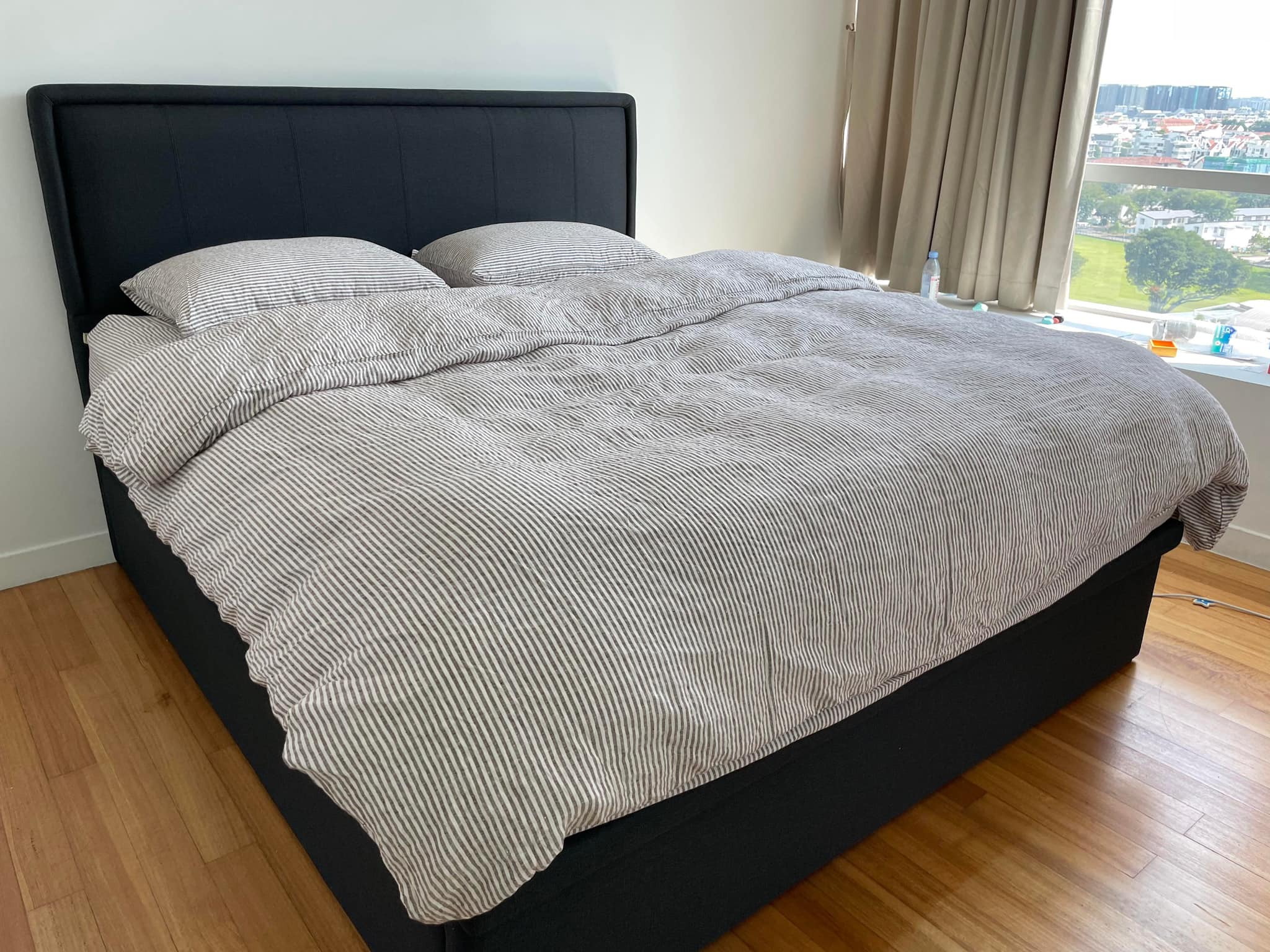 Grey striped yarn-dyed SCANDALINEN French linen duvet cover set on a black upholstered bed in a Singapore apartment with hardwood floors and city view
