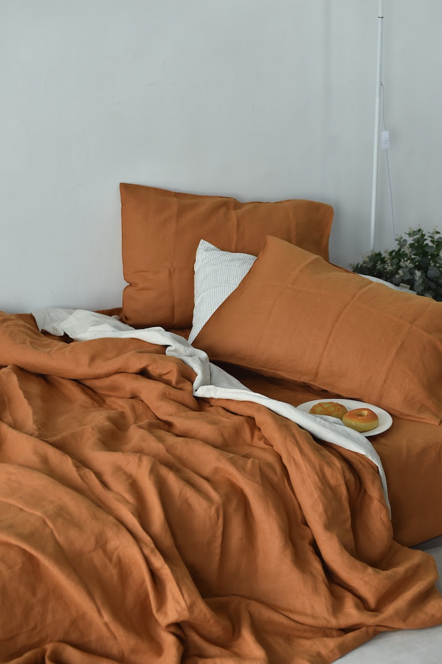 SCANDALINEN terracotta French linen duvet cover and pillowcases styled on a bed