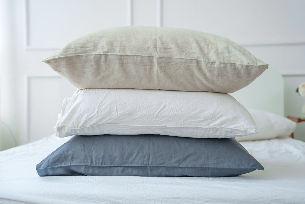 Beige, white and grey bamboo linen pillowcases stacked on a bed, 70% bamboo 30% linen - SCANDALINEN