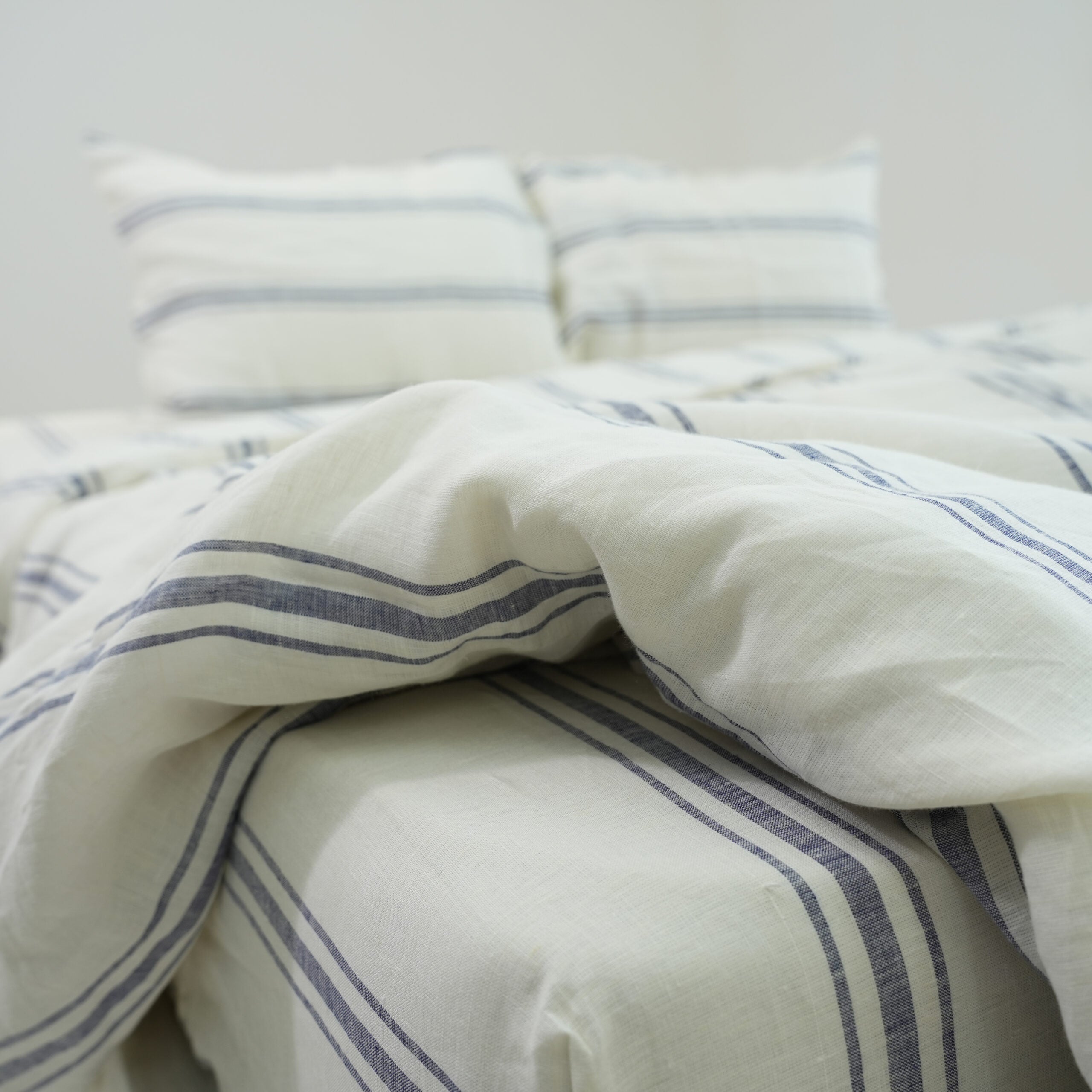 Ivory and navy striped French linen flat sheet on a bed, 100% European flax, stonewashed - SCANDALINEN