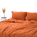 Orange French linen flat sheet on a bed, 100% European flax, stonewashed - SCANDALINEN
