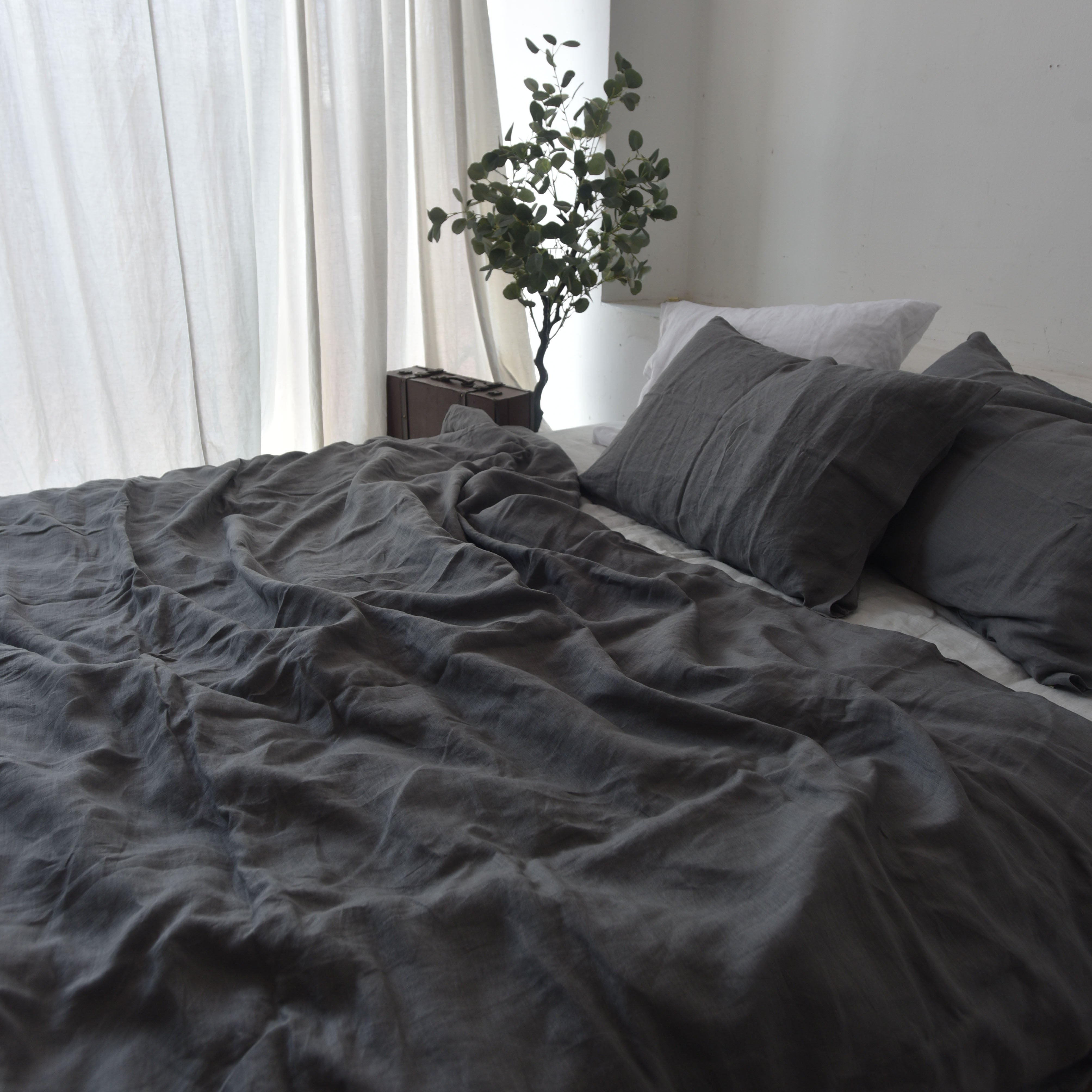 Dark teal French linen bedding neatly made on a bed - SCANDALINEN