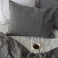 Charcoal French linen pillowcase on a bed, 100% European flax, stonewashed - SCANDALINEN