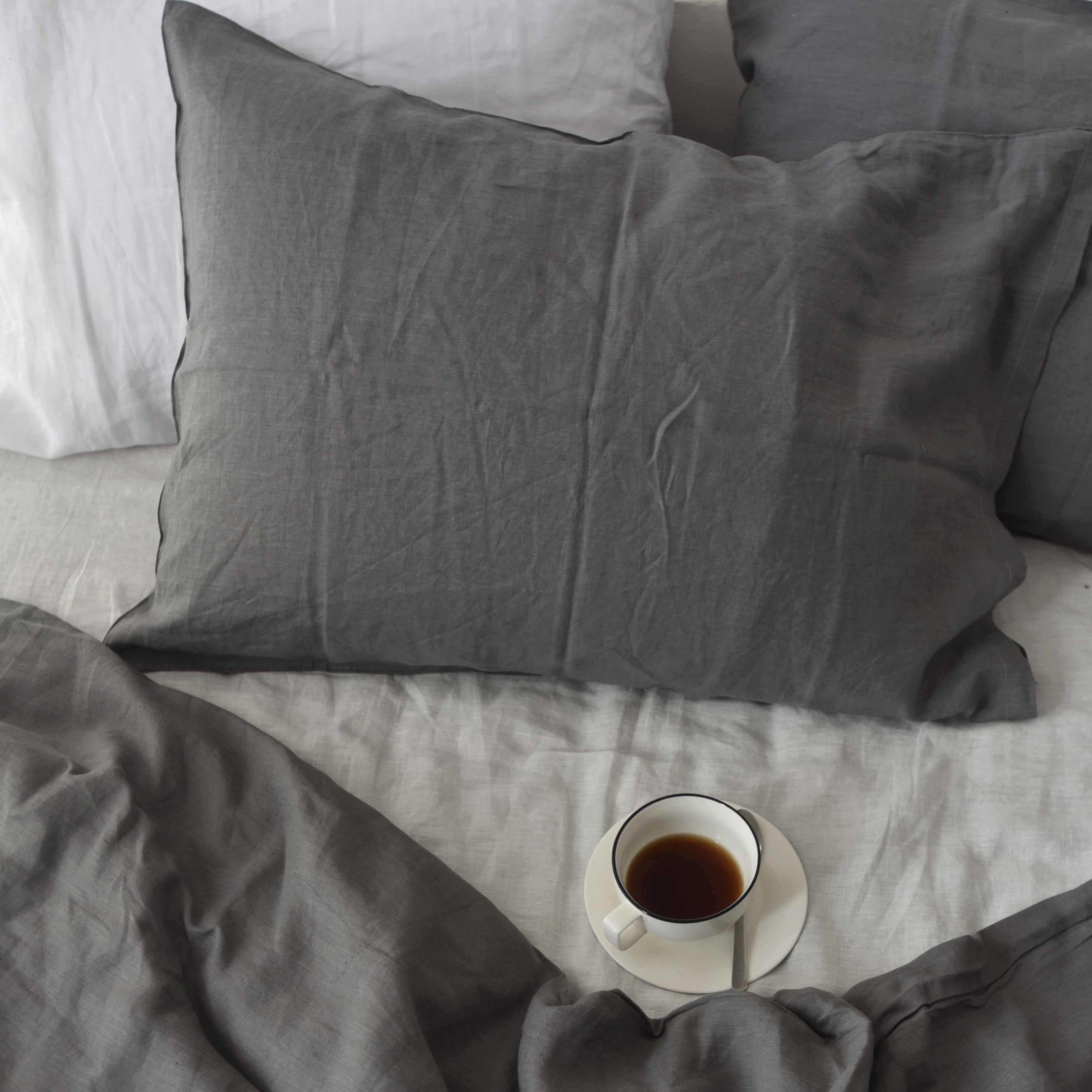Charcoal French linen pillowcase on a bed, 100% European flax, stonewashed - SCANDALINEN
